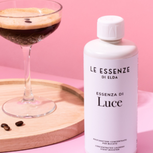 Fles geurversterker naast koffiedrank op houten dienblad.